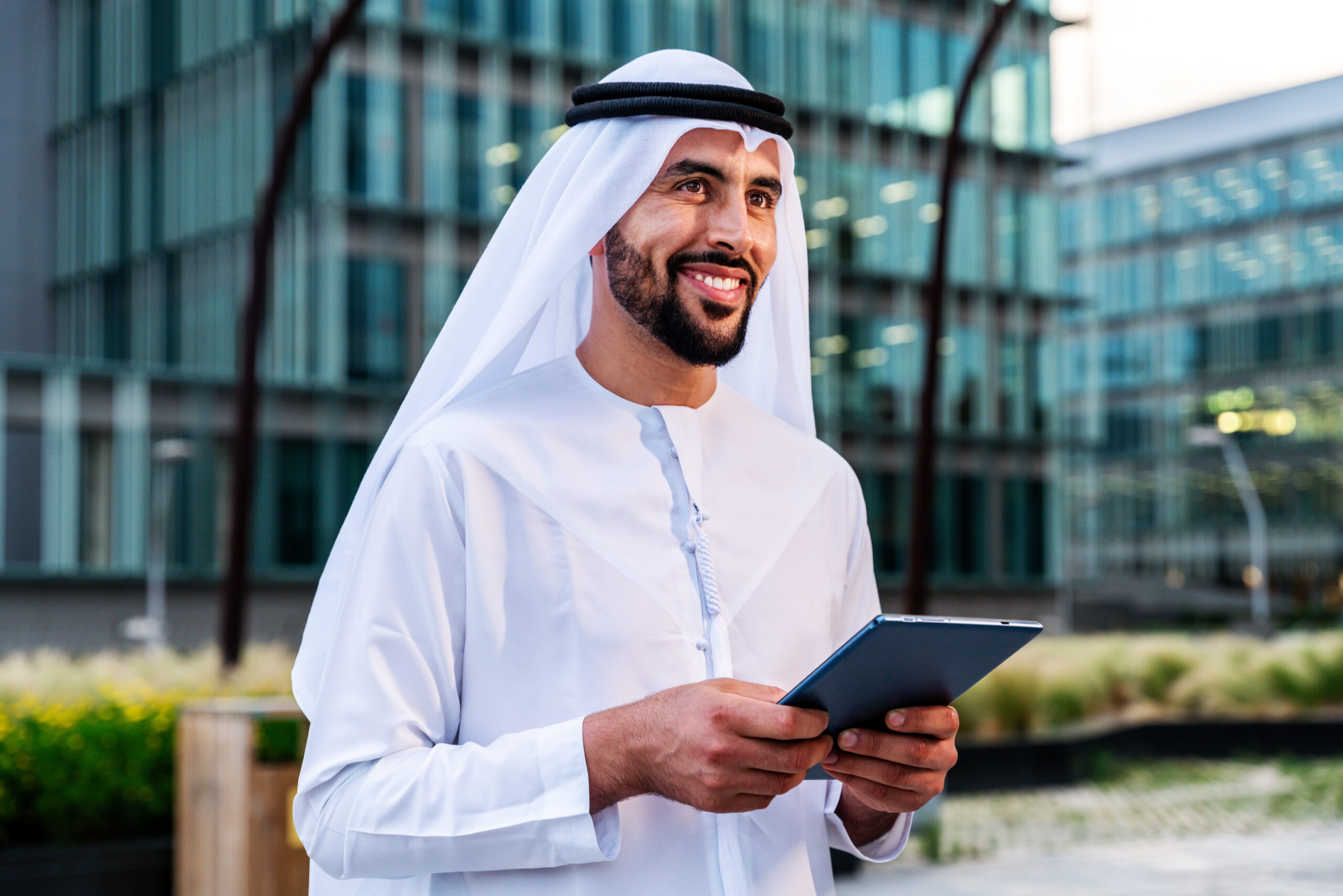 Arab middle-eastern man wearing emirati kandora traditional clothing in the city - Arabian muslim businessman strolling in urban business centre.