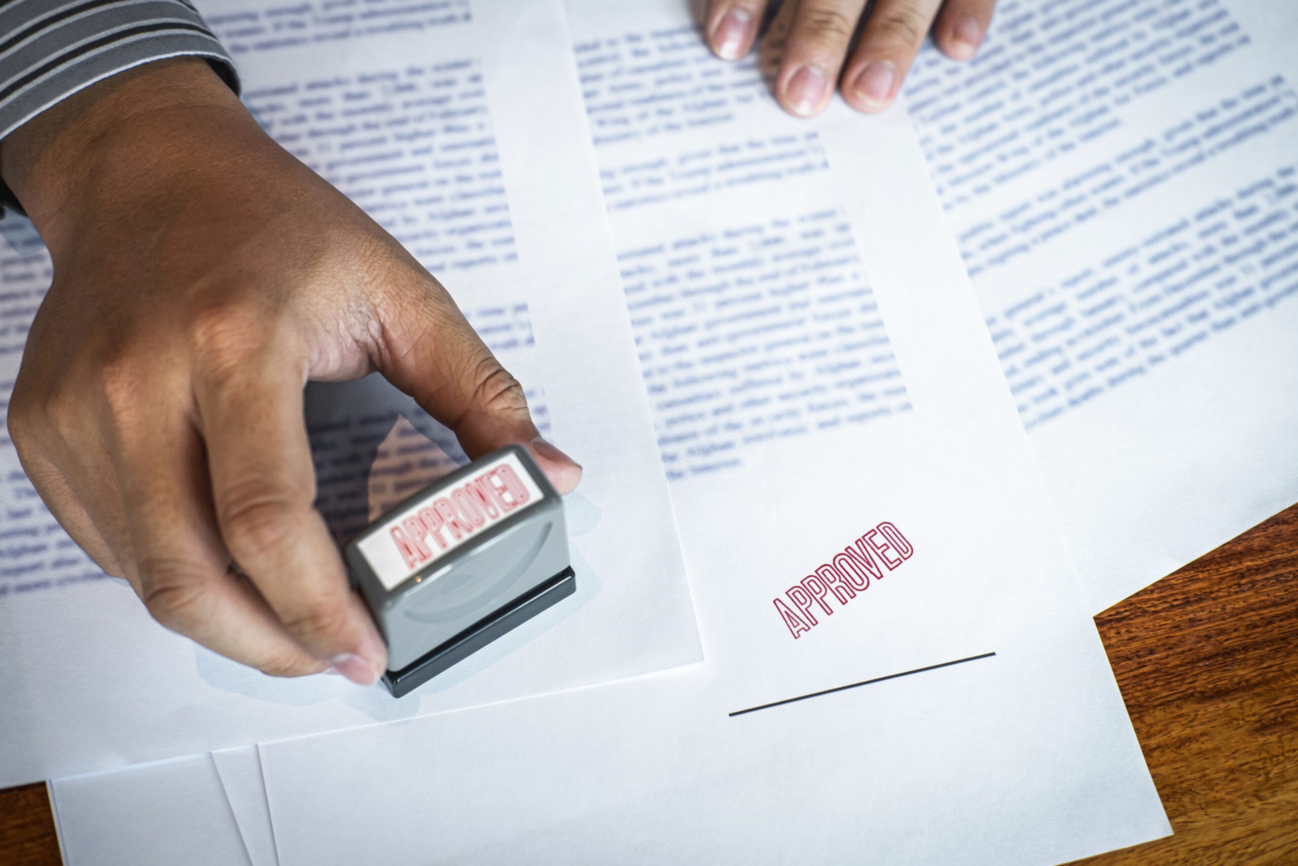 Hands of businessman stamp on paper document to approve business investment contract agreement.