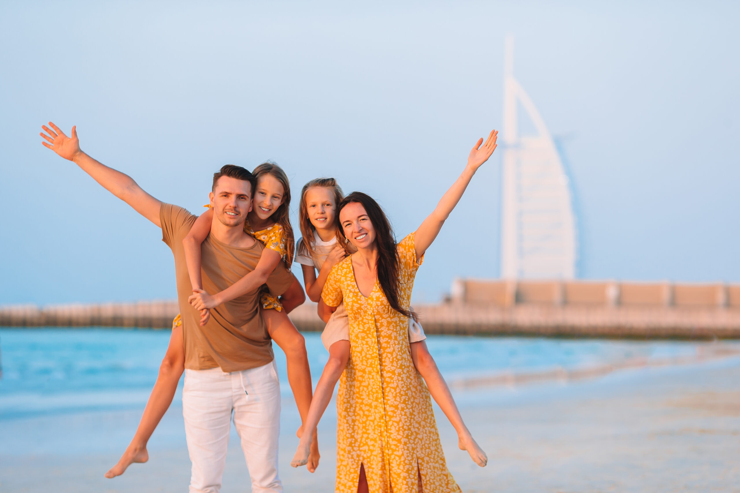 Happy family on the beach at summer vacation with Burj Al Arab on background in Dubai, UAE.